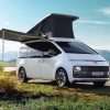 A white 2022 Hyundai Staria Lounge Camper with accessories in a grassy field