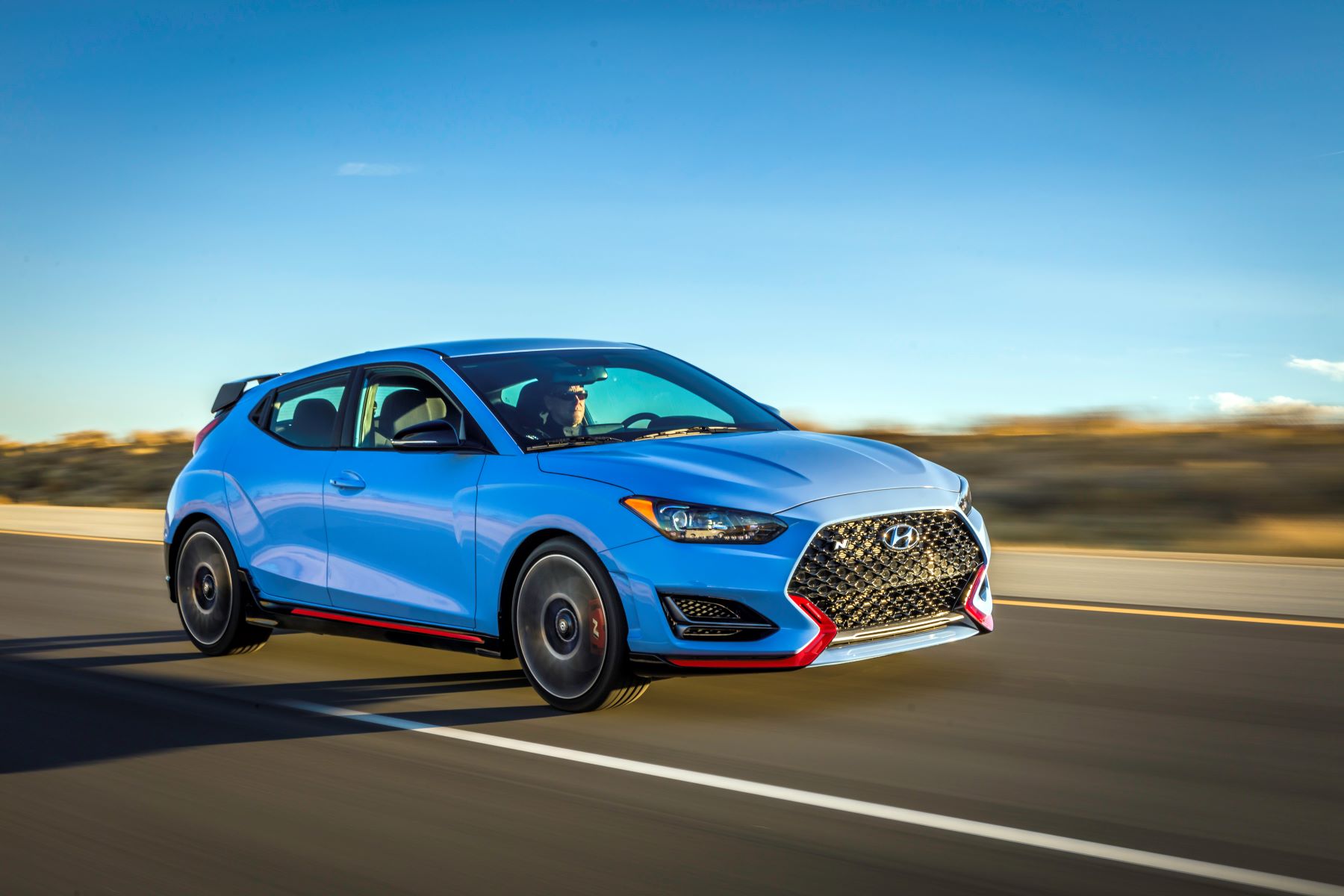 The 2022 Hyundai Veloster N performance hatchback speeding down a highway