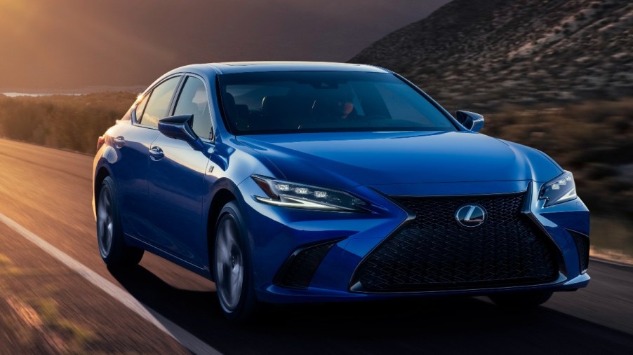 a blue 2022 Lexus ES drives down a desert road at sunset