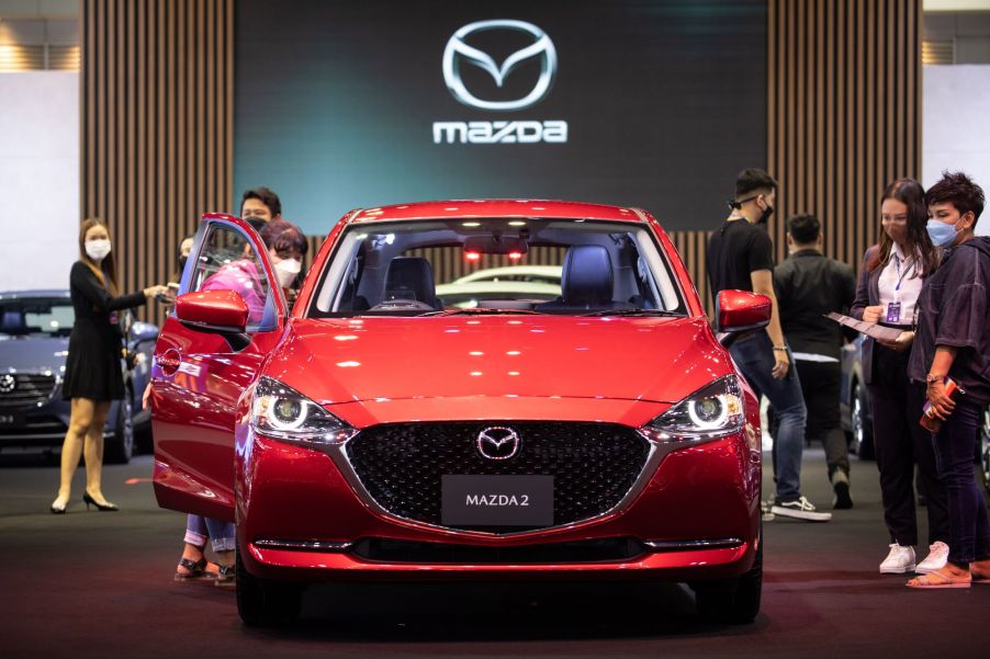 A red 2022 Mazda3 car indoors with the doors open.