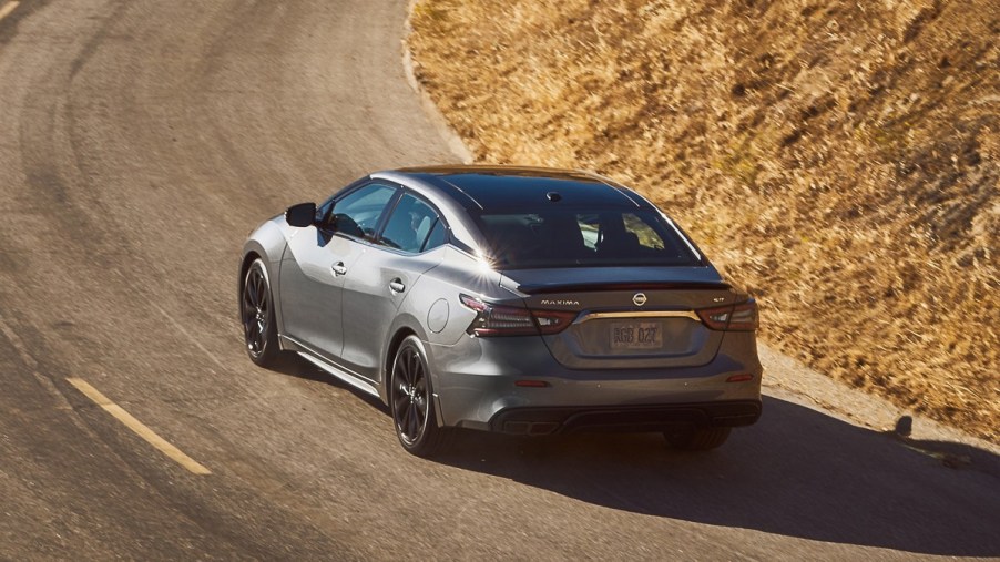 A new 2022 Nissan Maxima in grey driving on a road basked in sunlight