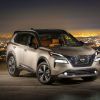 A silver 2022 Nissan Rogue in front of a night time city background.