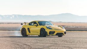 A yellow 2022 Porsche 718 Cayman GT4 RS sliding on a desert racetrack