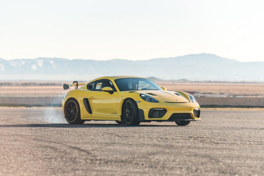 A yellow 2022 Porsche 718 Cayman GT4 RS sliding on a desert racetrack