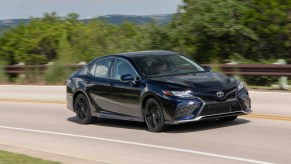 A blue 2022 Toyota Camry XSE drives along a winding road overlooking a mountain