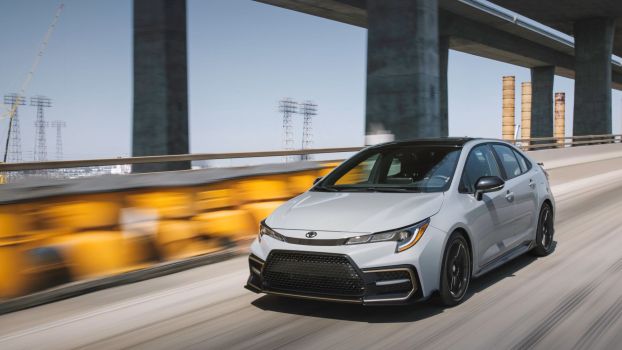 The 2022 Toyota Corolla Apex sedan driving near a highway overpass bridge