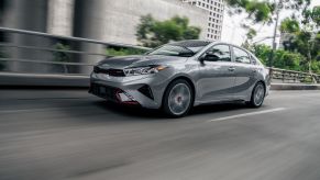 2022 Kia Forte GT-Line in Steel Gray driving along a paved road under a bridge