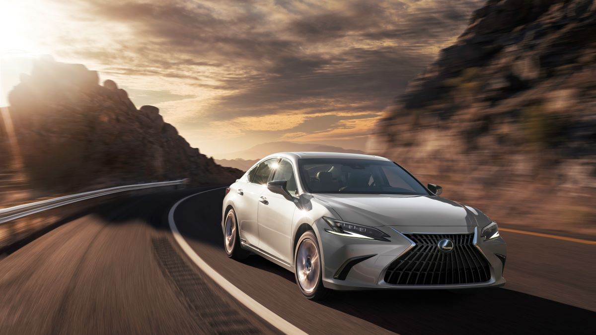 Silver 2022 Lexus ES Hybrid driving along a winding road at sundown; the ES is the best luxury hybrid car