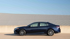 Side view of a dark blue 2022 Toyota Camry XLE Blueprint against a tan and light-blue background