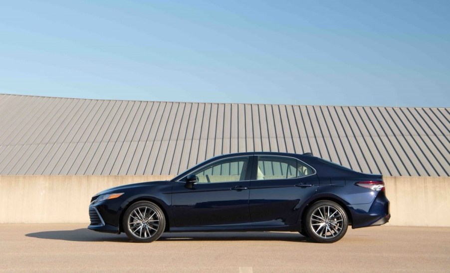 Side view of a dark blue 2022 Toyota Camry XLE Blueprint against a tan and light-blue background