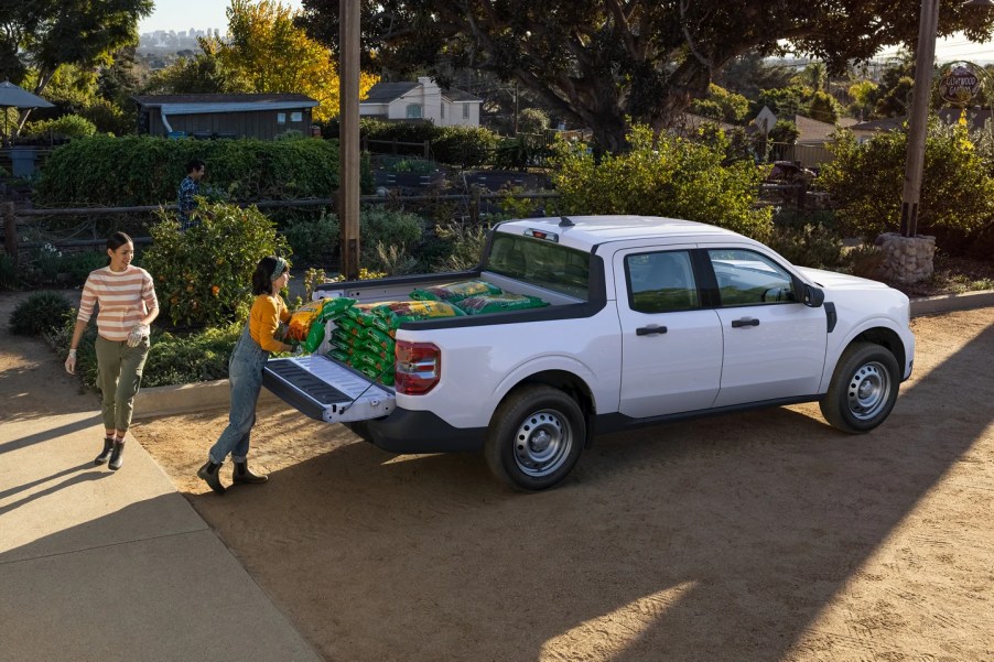 A white 2022 Ford Maverick sits atop steel wheels as garden soil is lowered into its bed.