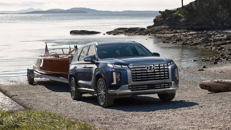 A dark blue 2023 Hyundai Palisade towing a boat out of the water.