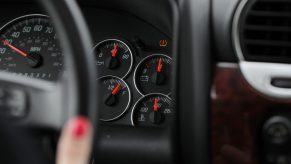 A GMC SUV's black gauge cluster with an illuminated TPMS light, indicating low pressure or sensor malfunction