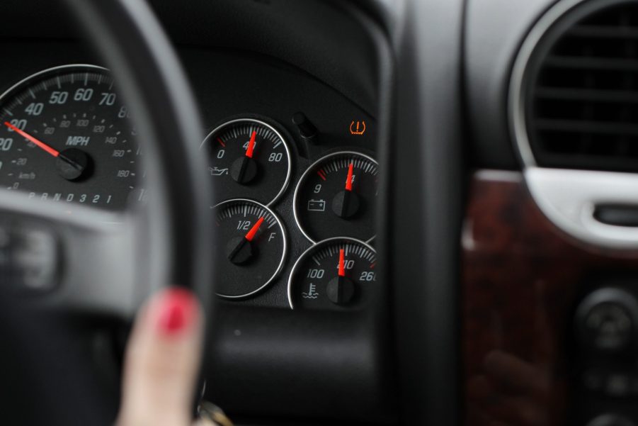 A GMC SUV's black gauge cluster with an illuminated TPMS light, indicating low pressure or sensor malfunction