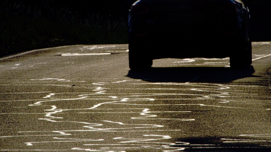 Car driving on road with black tar lines