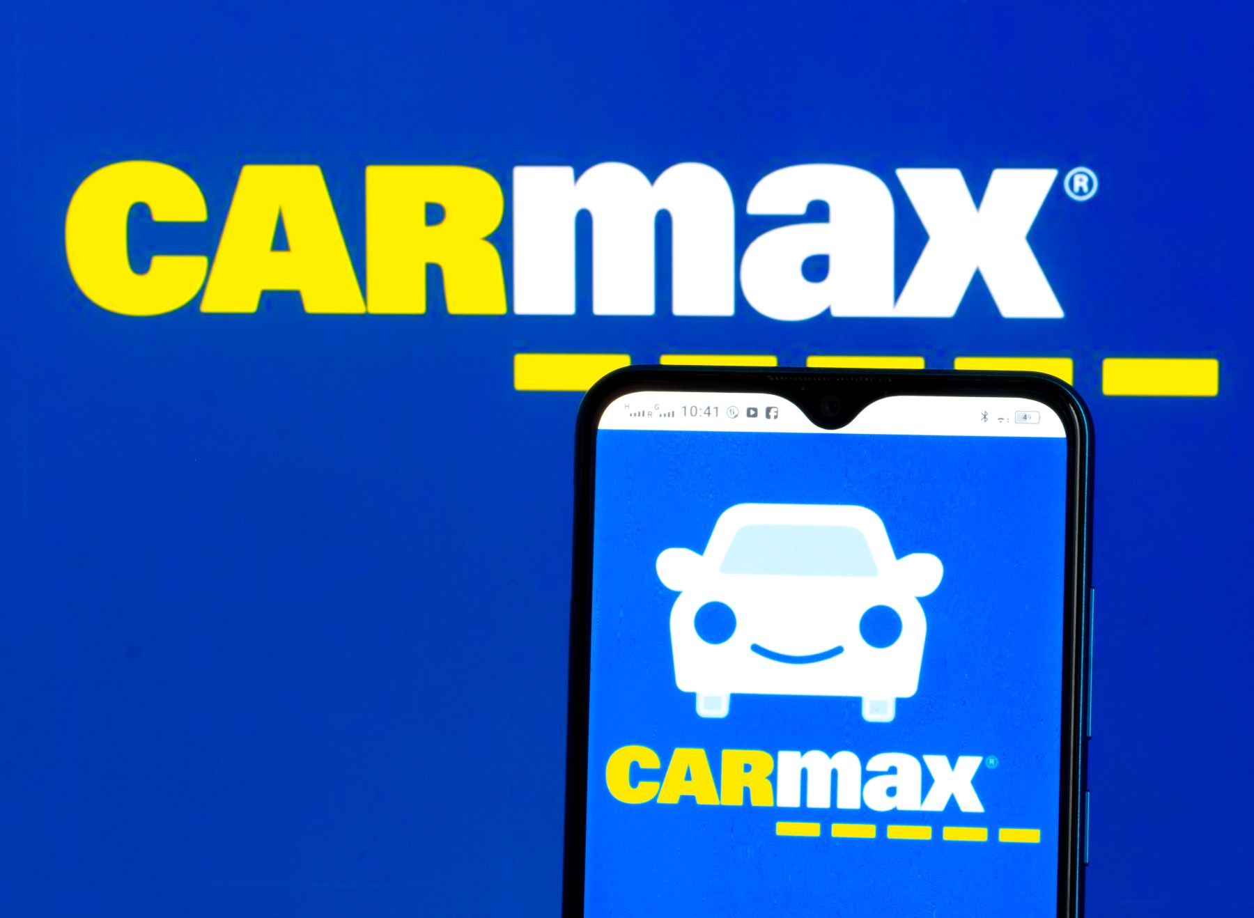 The CarMax logo on a smartphone and in the background