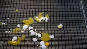 A bunch of broken eggs sitting on a grate after being thrown