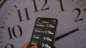 Daylight Savings Time graphic with a smartphone looking at World Clock app times with an analog clock in the background