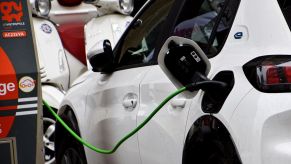 A white EV charging indoors at a charging station.