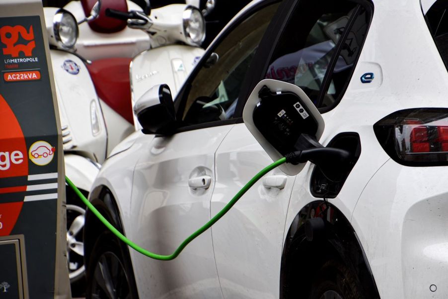 A white EV charging indoors at a charging station.