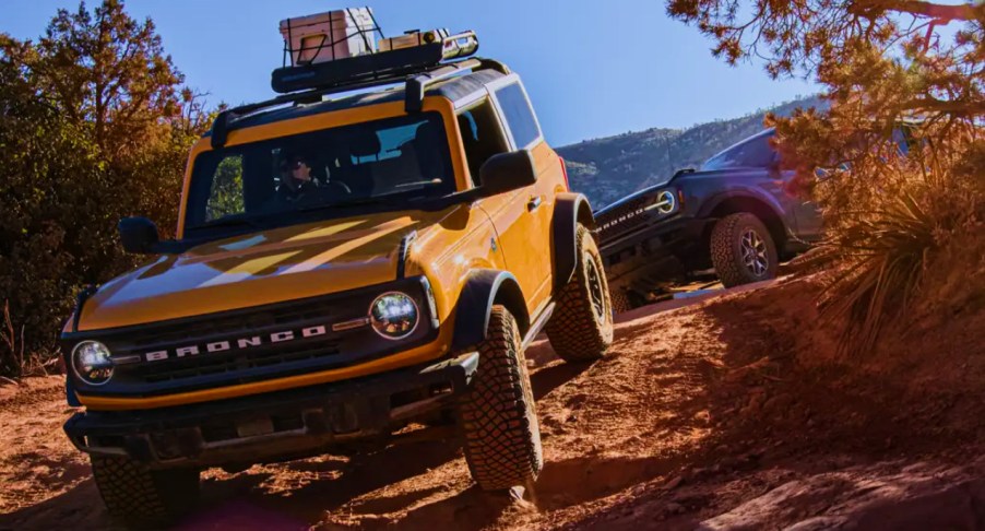 Two Ford Bronco small SUVs are off-roading.