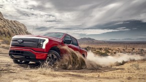 A 2022 Ford F-150 Lightning in red navigates a rugged terrain as an EV truck.