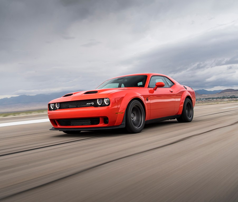 Dodge Challenger muscle car with a front-engine and RWD races down a highway.