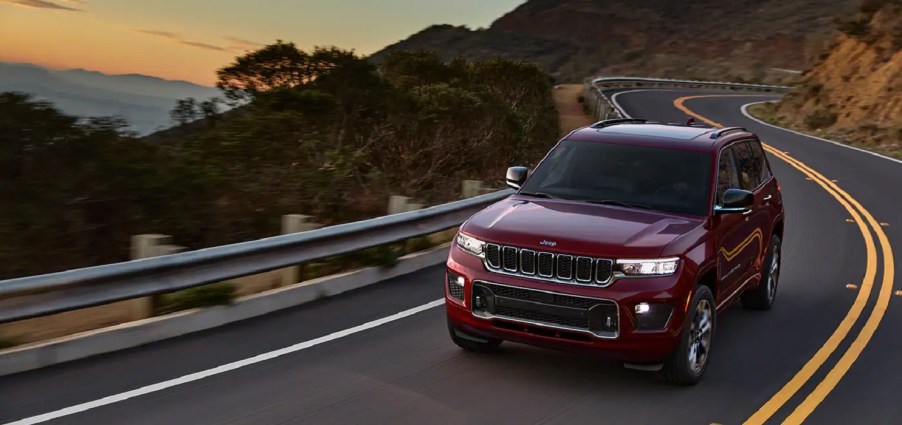 A red 2022 Jeep Grand Cherokee driving around a winding road.