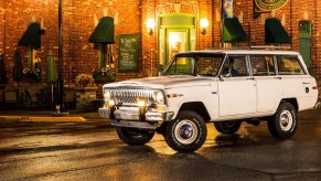 A white 1963 Jeep Wagoneer against a city.