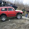 A red Lada Niva shows off its off-road capability as a 4x4 SUV on a dirt road.