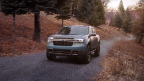 A 2022 Ford Maverick drives on a remote road as a compact pickup truck.