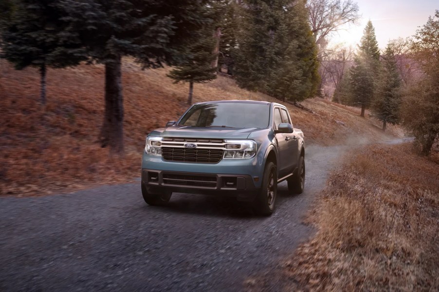 A 2022 Ford Maverick drives on a remote road as a compact pickup truck.