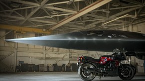 Maverick's red-and-black 1986 Kawasaki Ninja 900 by a gray fighter jet on the Top Gun: Maverick set