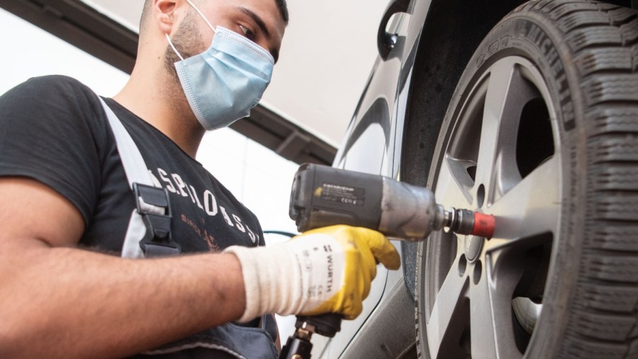 A mechanic takes the tire off of a car with a impact driver to do a tire rotation