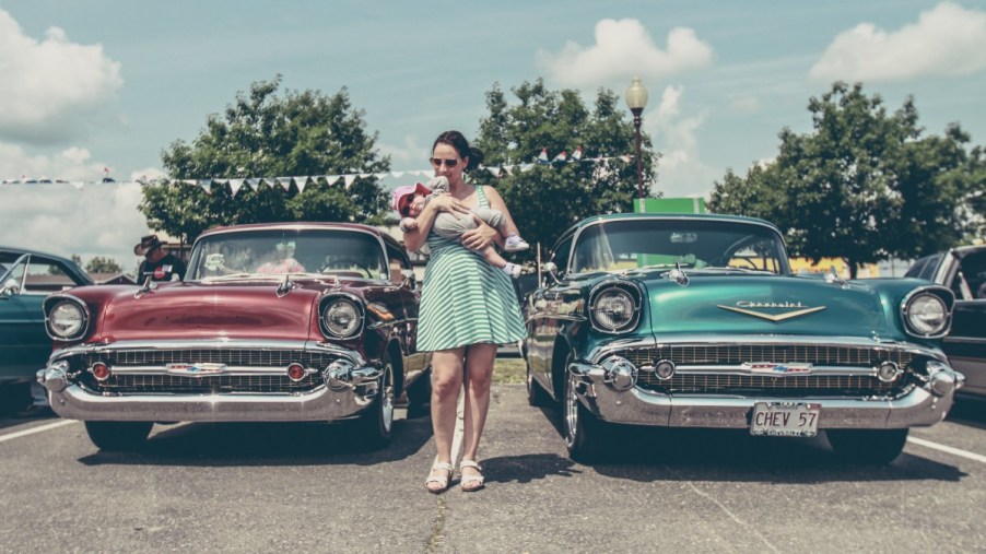 Mother with child next to classic cars, highlighting Hands of the Carpenter charity that gives cars to single mothers