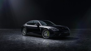 A black 2022 Porsche Panamera 4 E-Hybrid Platinum Edition parked in a dark room with bright lighting brining it into view