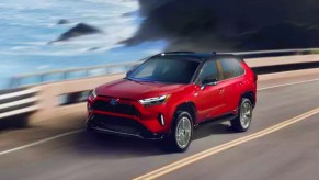 A red 2022 Toyota Rav4 driving along a coast road proves Toyota makes the best Hybrid SUVs