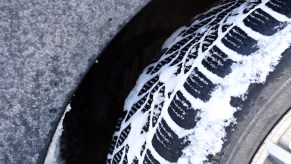 Closeup of winter tires full of snow, demonstrating how they maintain traction via a contact patch extending past the snow