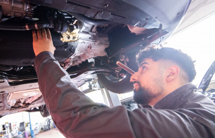 An auto mechanic working under a raised Volkswagen Touran vehicle in Lower Saxony