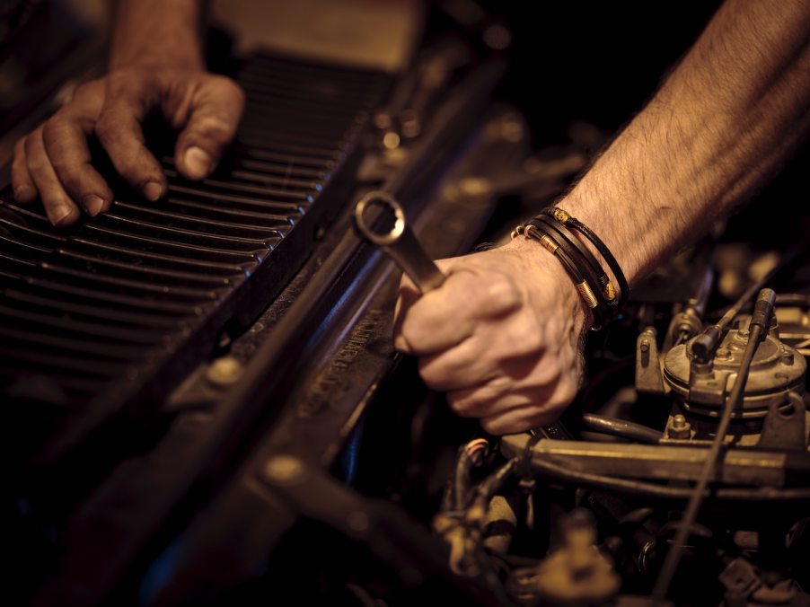 Closeup of a mechanic working on an old car.