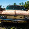 Junkyard parts surrounding a rusted old car in a scrapyard