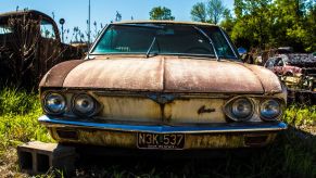 Junkyard parts surrounding a rusted old car in a scrapyard