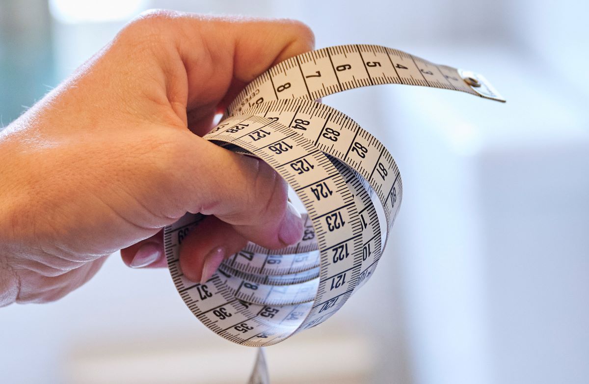 Close-up of a person's hand tightly holding a wrapped cloth measuring tape