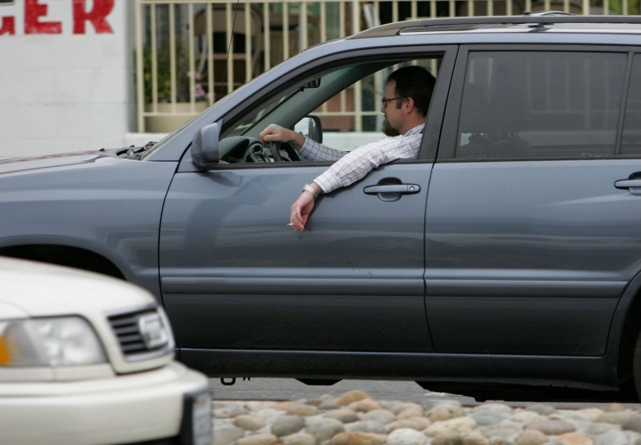 A man hangs a cigarette out of his car window