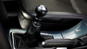 A manual transmission gear select inside of a vehicle with black interior.