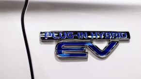 A plug-in hybrid EV badge on a Mitsubishi Outlander PHEV SUV