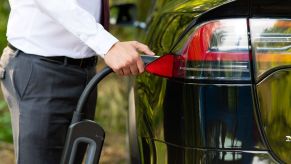 A man plugging-in the charging cable to his Tesla Model X electric vehicle (EV)