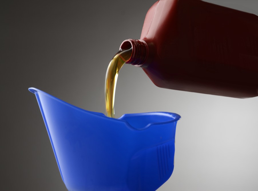 Close-up view of motor oil as it is poured from a red container into a blue bucket