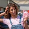 A new driver holding a new driver caution sign to display on her car after passing the driving test