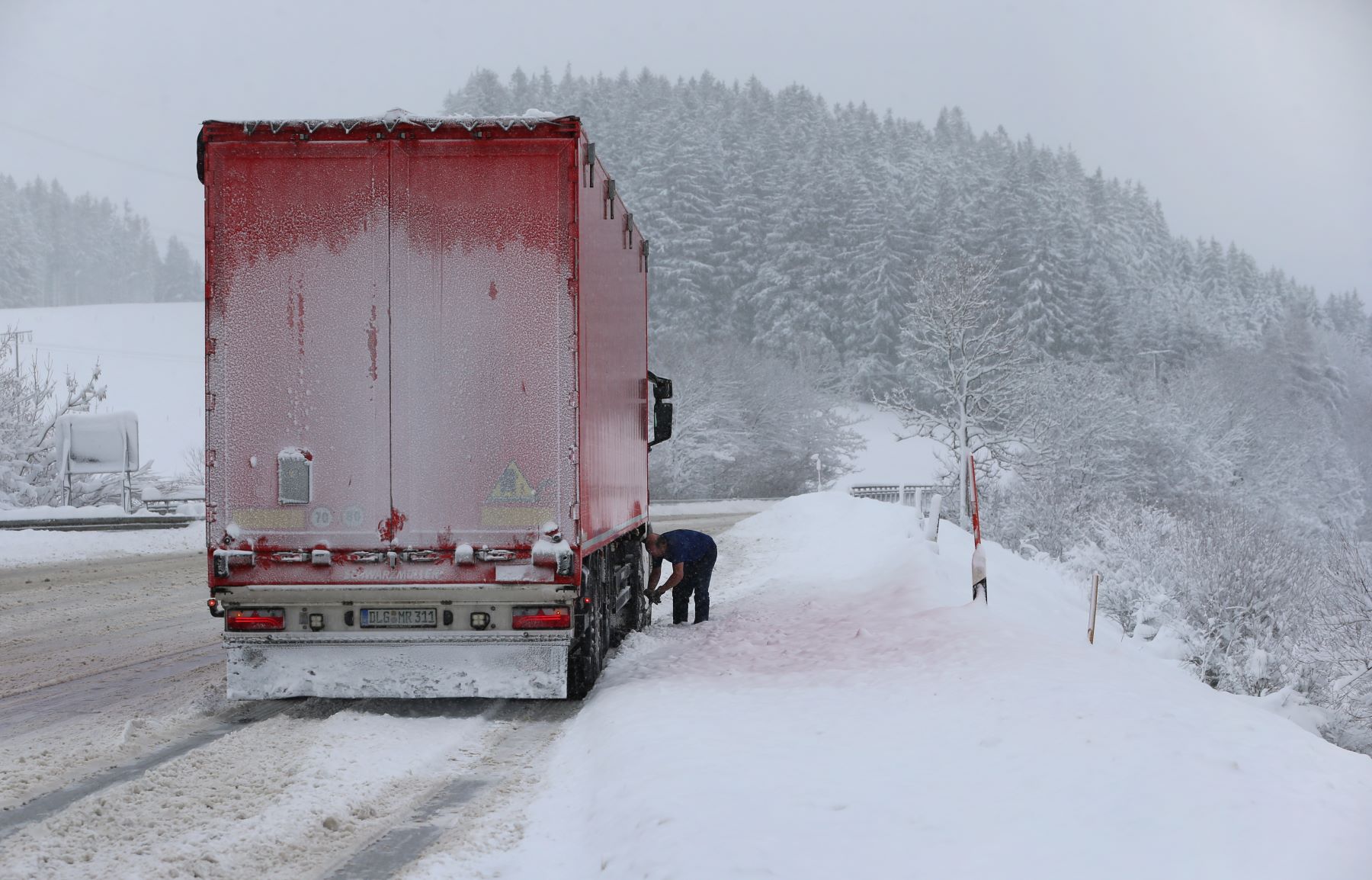 A trucker adding snow chains to tires during a winter drive in Bavaria, Wildpoldsried